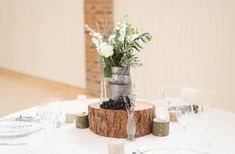 a table with flowers and candles on it that says how to style a milk churn wedding centerpiece