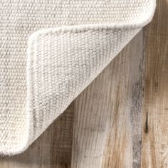 a white rug on top of a wooden floor next to a wood planked wall