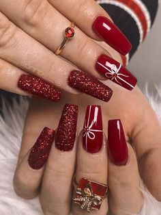 a woman's hands with red and gold nail polishes on their nails, holding a christmas present