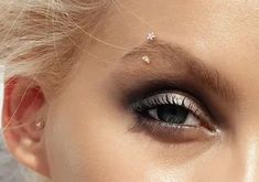 a close up of a woman's face with makeup and eyeliners on