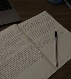 an open notebook with writing on it next to a laptop