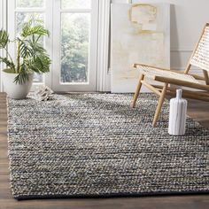 a living room area with a chair, rug and potted plant