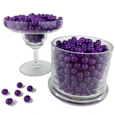 there are many purple balls in the glass bowl next to each other on the table