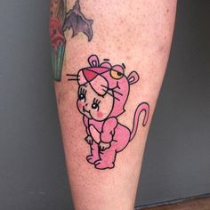 a small tattoo on the leg of a person with a pink cat and flowers in the background