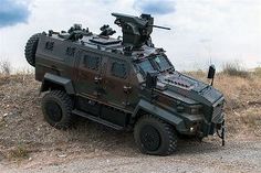 an armored vehicle parked on the side of a dirt road in front of a cloudy sky