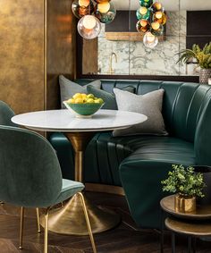 a living room with green leather couches and round table surrounded by hanging glass globes