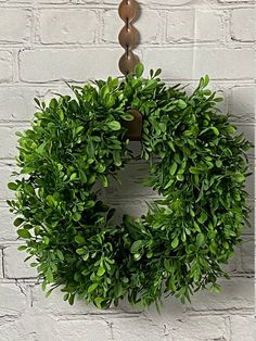 a green wreath hanging on a brick wall