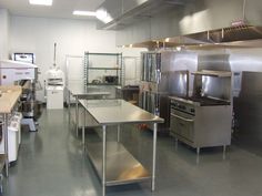 an industrial kitchen with stainless steel appliances and counters in the center, along with other equipment