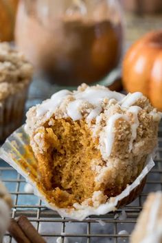 a cupcake on a cooling rack with frosting and pumpkins in the background