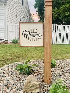 a sign that is in the middle of a rock garden area next to a house