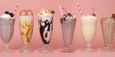 five different types of milkshakes lined up on a pink background