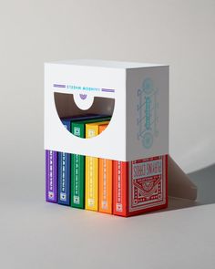 a stack of brightly colored books sitting on top of each other in front of a white box