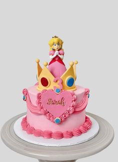 a pink cake with a princess on top and a heart shaped crown in the middle