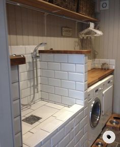 a washer and dryer in a small room with shelves on the wall behind them