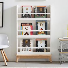 a white book shelf filled with books next to a desk and chair in a room