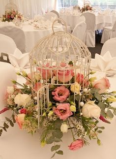 a birdcage filled with flowers on top of a table