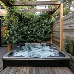 a hot tub sitting on top of a wooden deck next to a green planter