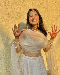 a woman in a white outfit with painted hands on her chest and arms, posing for the camera