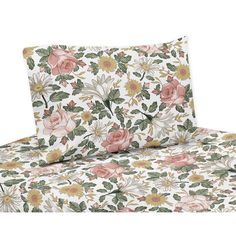 a bed with floral sheets and pillows on top of each other, one has pink flowers