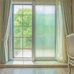 an empty chair sitting in front of a window with curtains on the outside and inside