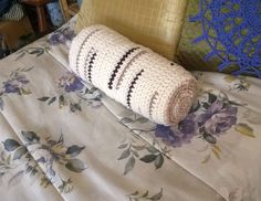 a crocheted blanket laying on top of a bed next to pillows and blankets