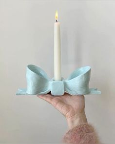 a person holding a candle in their hand with a light blue bow on the top