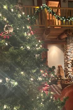 a decorated christmas tree in front of a stone fireplace