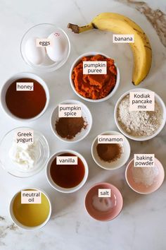 an assortment of ingredients in small bowls on a marble counter top, including bananas and pumpkin spice