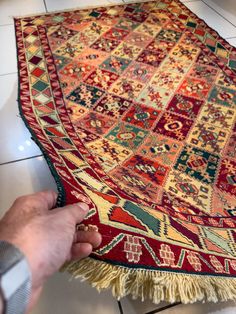 a person is touching the rug on the floor with their hand and pointing at it