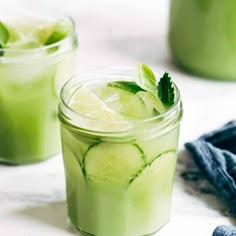 a glass filled with limeade and mints on top of a wooden table