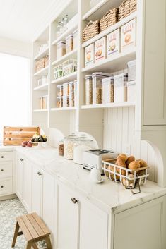 a kitchen filled with lots of white cupboards and counter top covered in food items