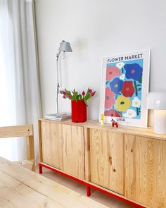 a wooden cabinet with flowers on it next to a lamp