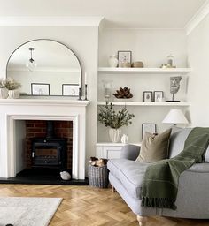 a living room filled with furniture and a fire place under a mirror on the wall