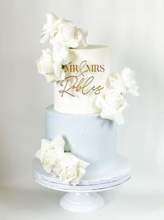 a three tiered cake with white flowers on top and the words mr and mrs written on it