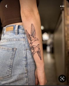 a person with a bird tattoo on their left arm and the other hand behind her back