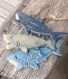 three ceramic shark ornament hanging on a wooden plank