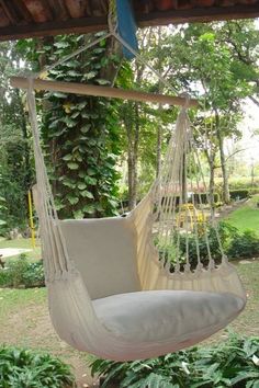 a white hanging chair in the middle of a garden with plants growing on the wall