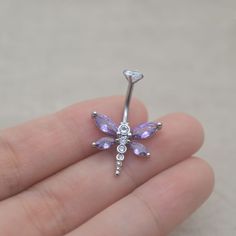 a person is holding a tiny purple dragon belly ring with clear crystals on the side