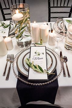 a table set with place settings, candles and napkins for an elegant dinner party