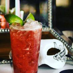 a red drink sitting on top of a table next to a white skull face mask