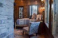 a bedroom with a bed, chair and fireplace in the corner next to a window