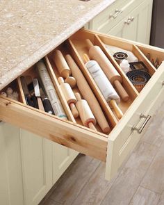 an open drawer in a kitchen with wooden utensils and other items inside it