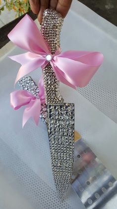 a hand holding a pink and silver vase with a bow on it's side