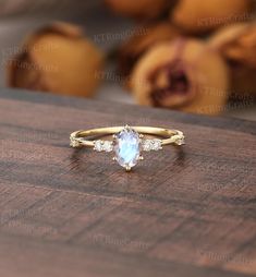 a gold ring with an oval blue topazte surrounded by small white diamonds on a wooden surface