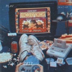 a person is sitting in front of a video game playing machine with his feet up on the table