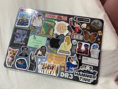 an apple laptop covered in stickers on a bed