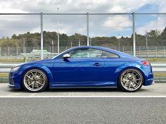 a blue sports car parked in front of a fence