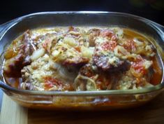 a casserole dish with meat and vegetables in it sitting on a wooden table