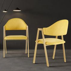 two yellow chairs sitting next to each other on a gray floor in front of a black wall