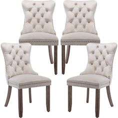 four white dining chairs with buttons on them